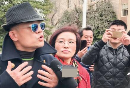 周立波(戴帽者)2017年被控罪后在长岛纳苏郡地区法庭外接受记者访问。(图源:侨报)