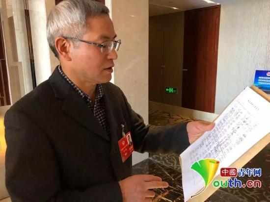 全国政协委员贺云翱发起这份联合提案,图为提案最终递交前他向记者介绍签名情况