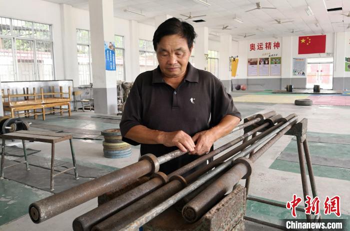  图为唐运桂在整理举重训练器材。　赵琳露　摄